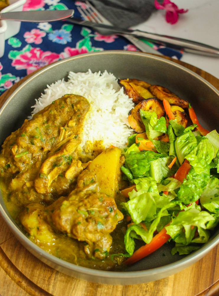 plate of Caribbean Curry Chicken with rice, salad and fried plantain