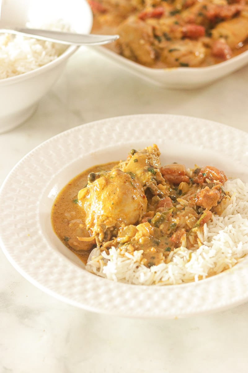 Chicken Curry with Rice in a bowl . Additional bowls with chicken and rice seperately in background.