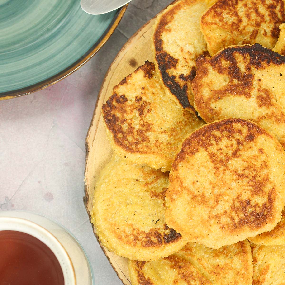 Cornmeal Pancakes on a plate with a cup of tea on the side