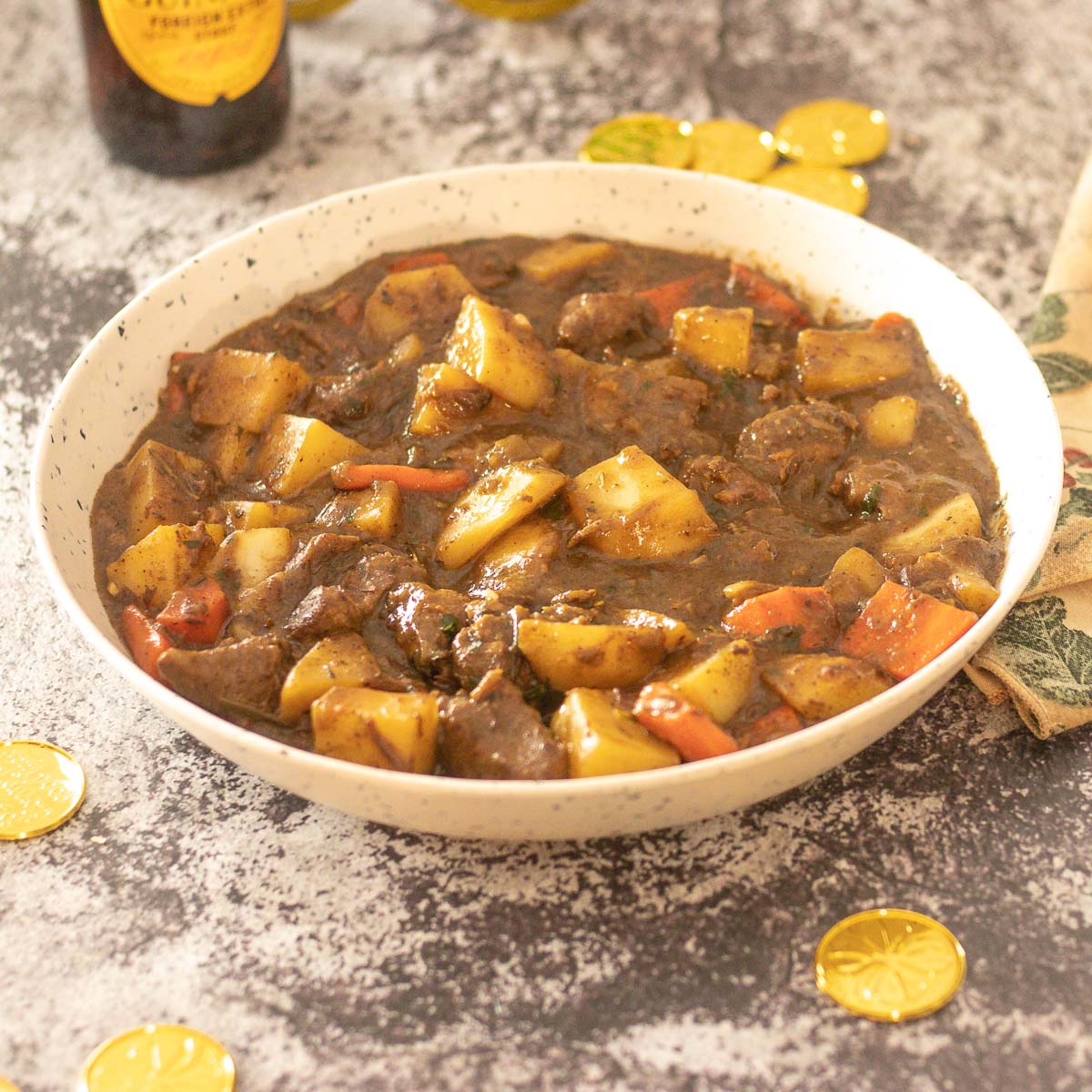 bowl of Irish Lamb Stew with bottle of Guinness in the background