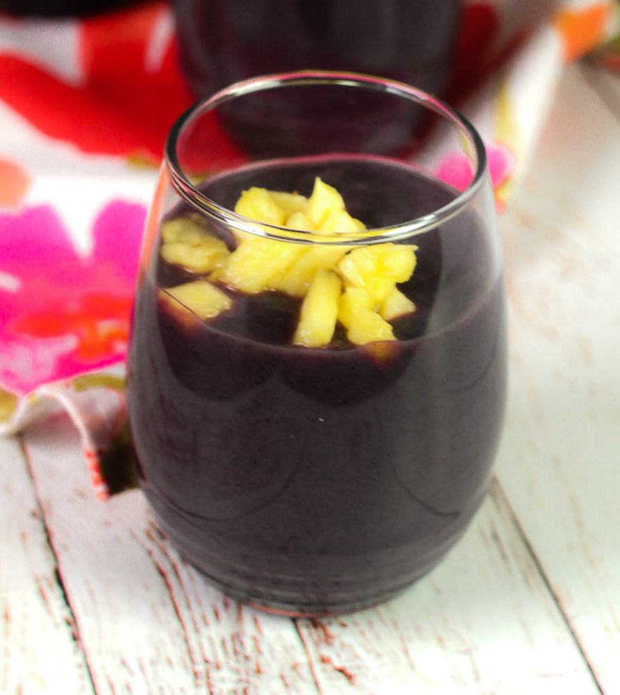 glass of blue cornmeal drink with chopped pineapple