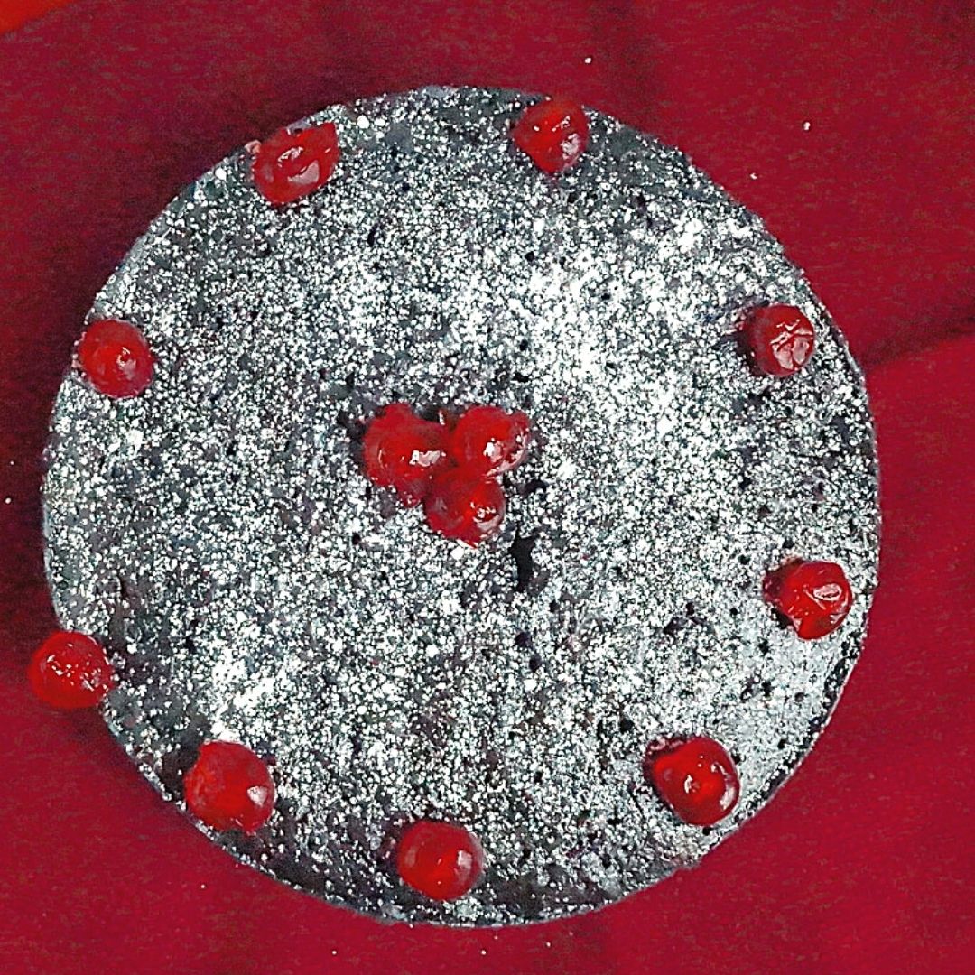 Caribbean Fruit Cake decorated with glace cherries and powdered sugar