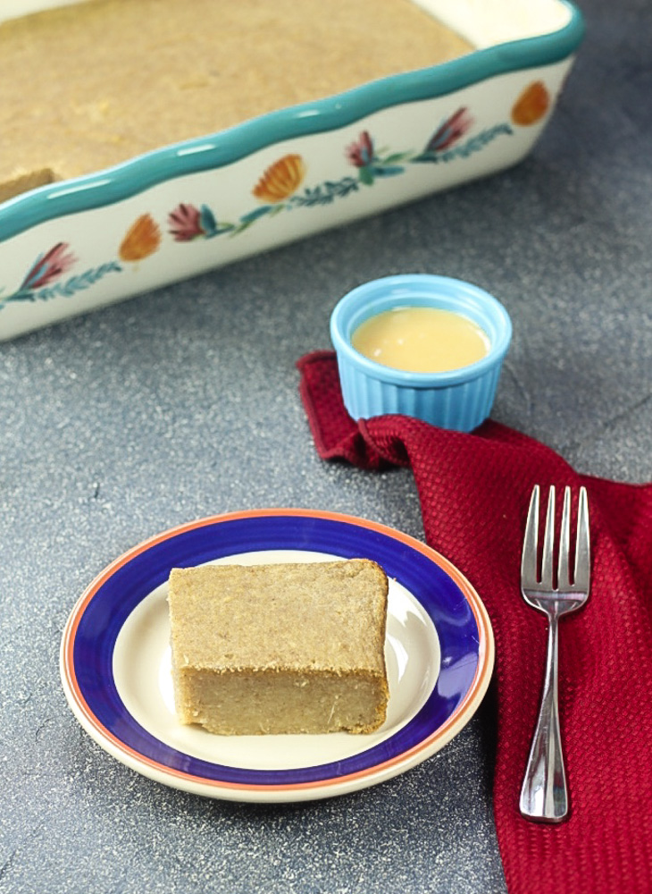 slice of gluten free cassava cake with a fork and sweetened condensed milk in a ramekin