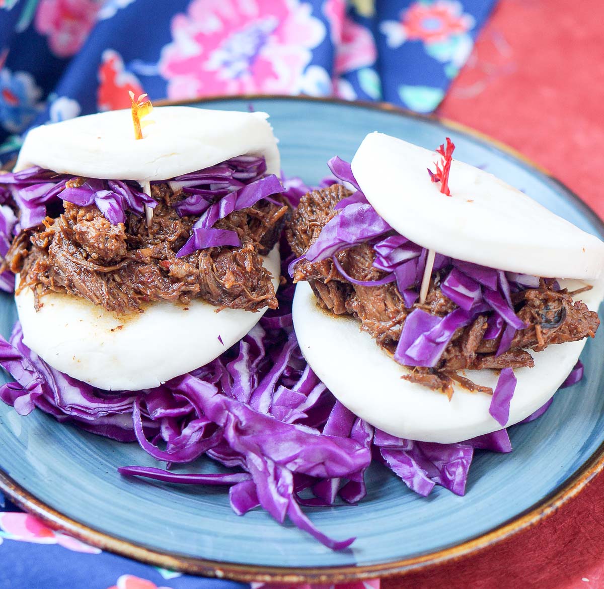 2 bao sandwiches with red curry milk pork and garnished with purple cabbage