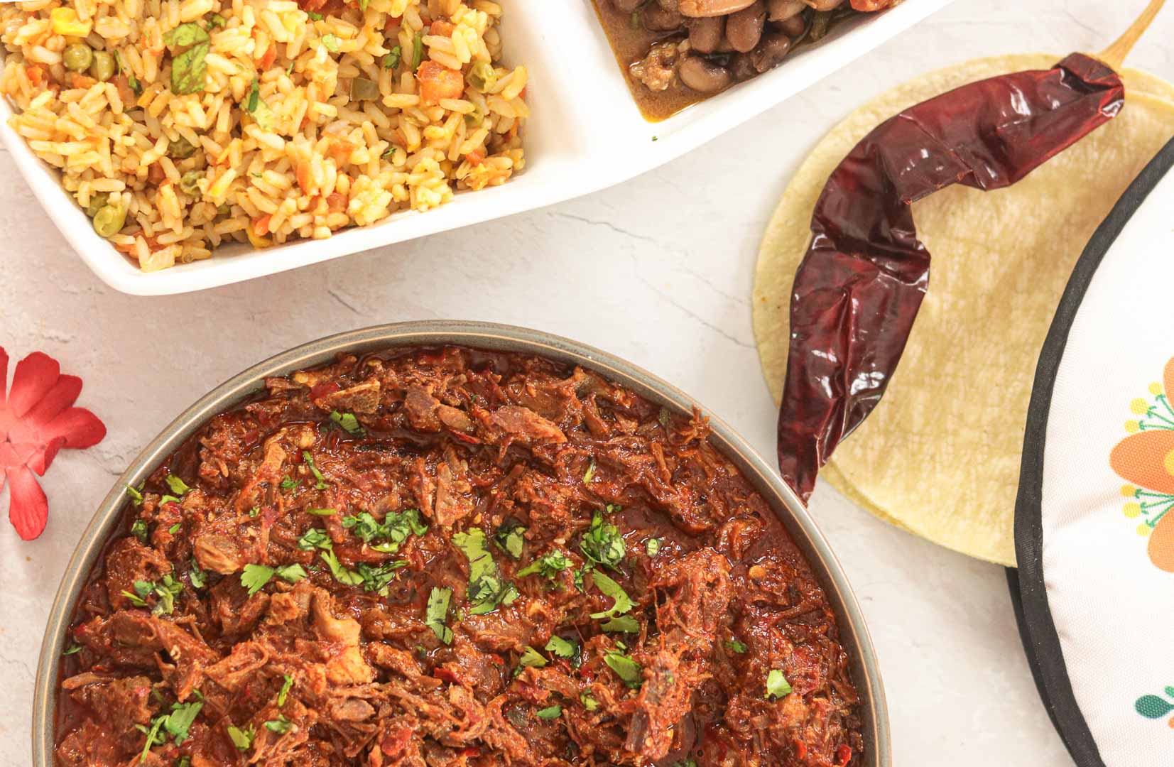 Birria with guajillo chillies and Mexican Rice in background.