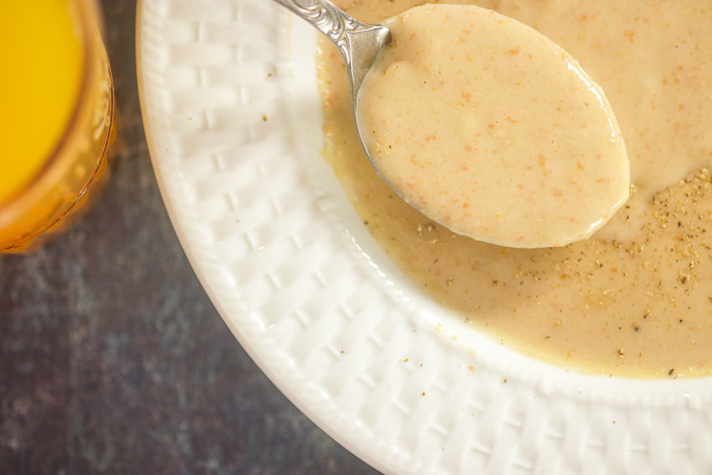 spoon of Haitian Plantain Porridge on top of bowl of Labouyi Porridge