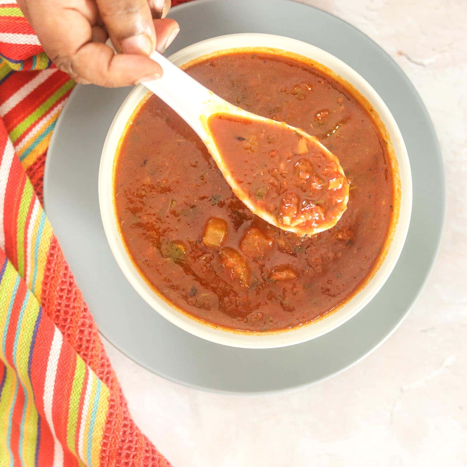 Creole Sauce in bowl with spoon and kitchen towel