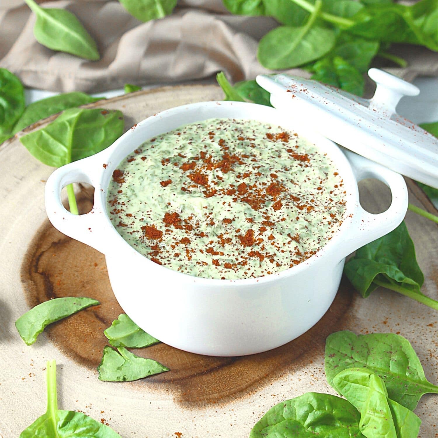 5 minute Spinach Dip Recipe in a bowl on a wooden platter with spinach leaves garnish