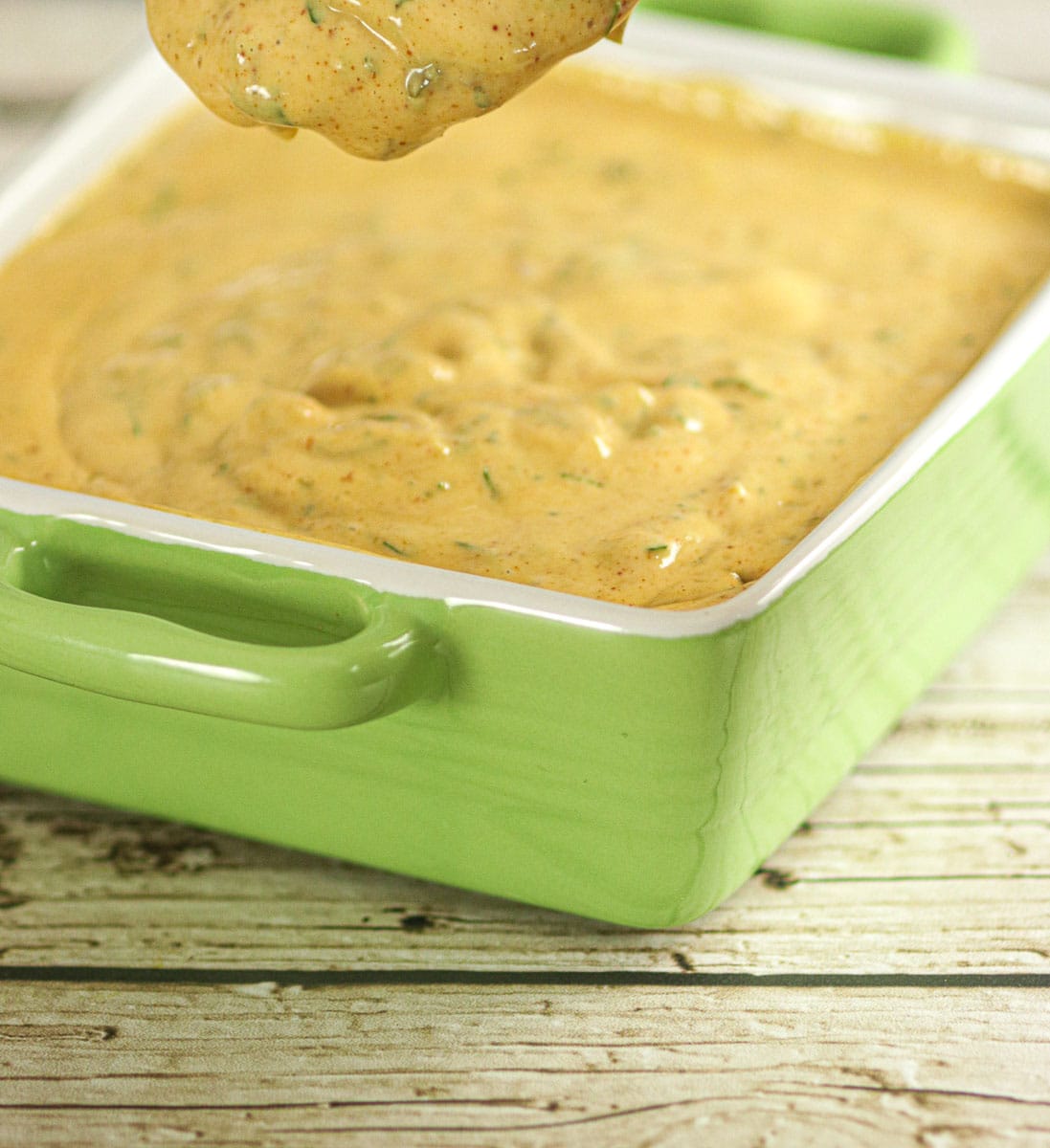 Remoulade dripping off a spoon over a bowl