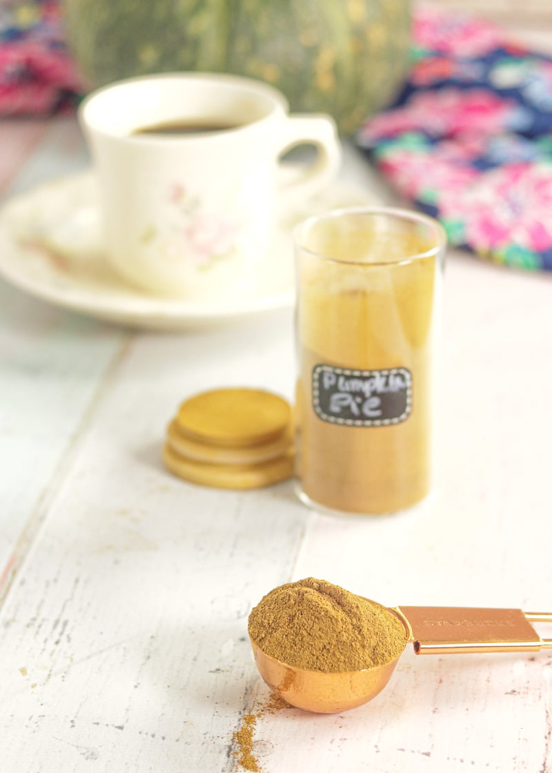 Pumpkin Spice Mix on a spoon with a jar and a cup of coffee in the background