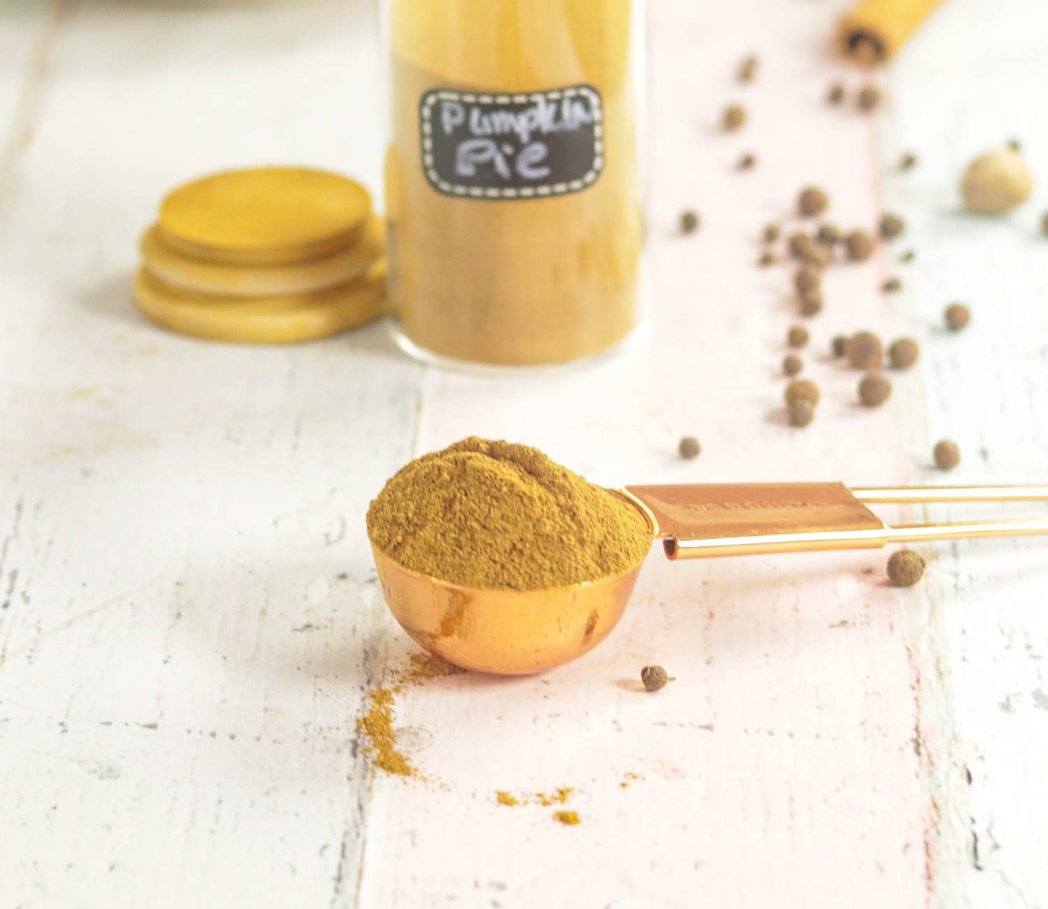 Pumpkin Pie Spice Mix on a spoon with whole spices in the background