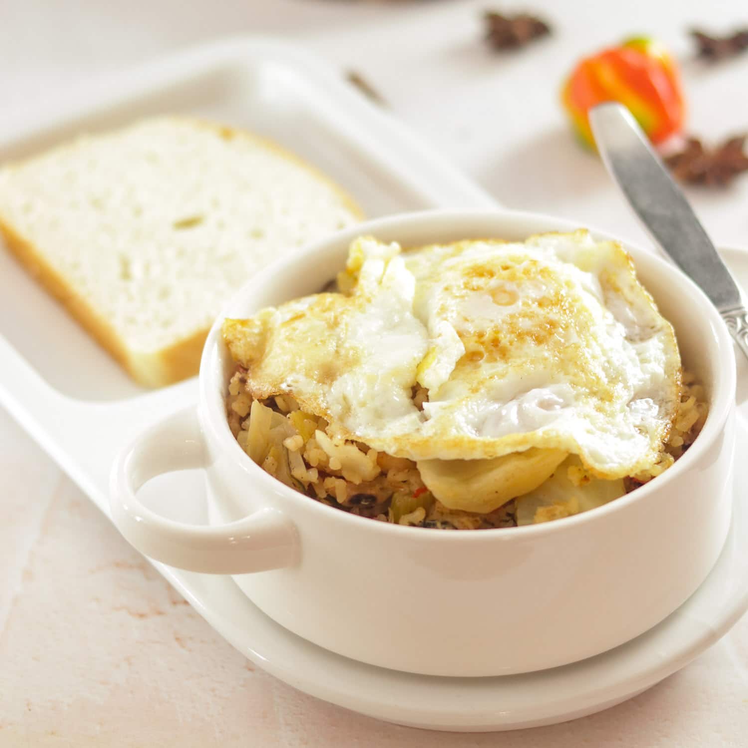 rice and chicken topped with a fried egg with a slice of bread in a bowl