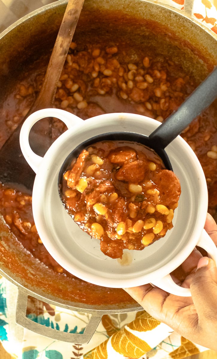 ladle of white bean stew pouring into bowl