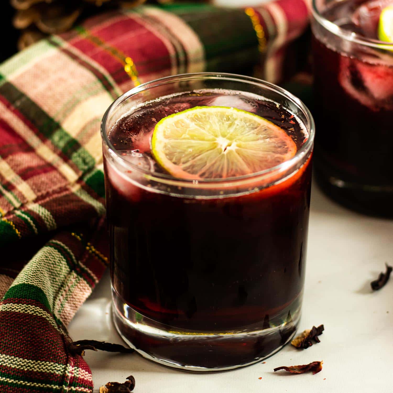 Hibiscus Rum Punch in a glass with lime and pink peppercorn garnish