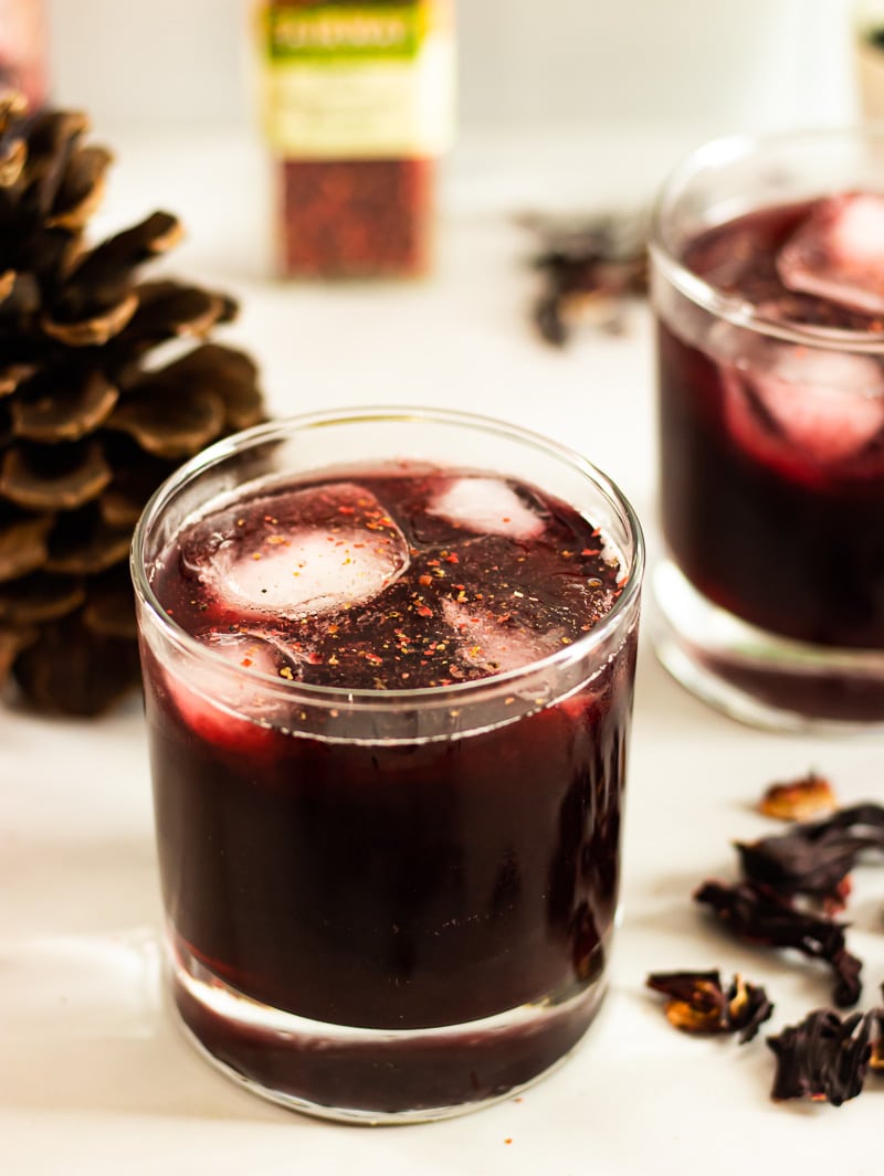 Hibiscus Concentrate is mixed with liquor for the best holiday cocktail with a mild spicy kick from the pink peppercorn garnish! #rumpunch #sorrel #christmaspunch