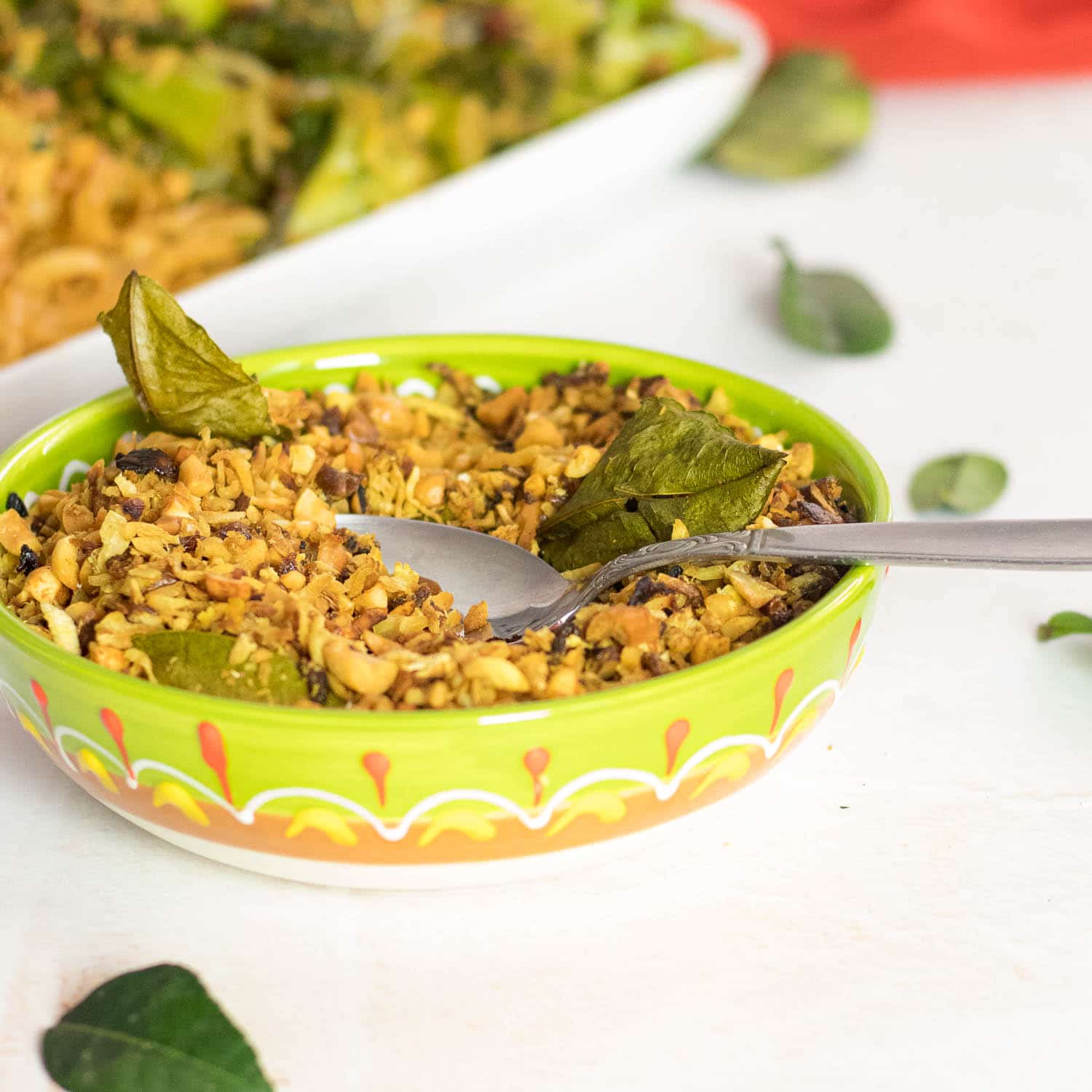 bowl of Indonesian Seroendeng - Coconut Peanut Crumble in a bowl with kaffir lime leaves