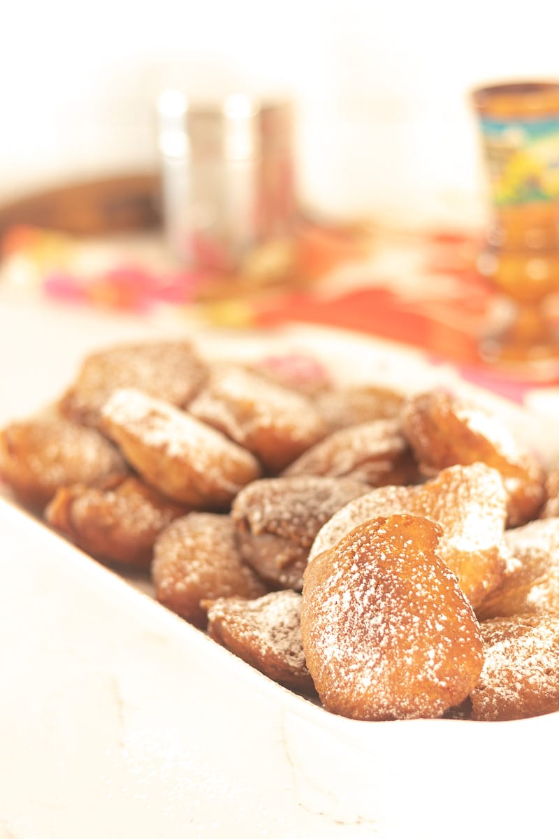 a plate of Haitian style beignet with powdered sugar