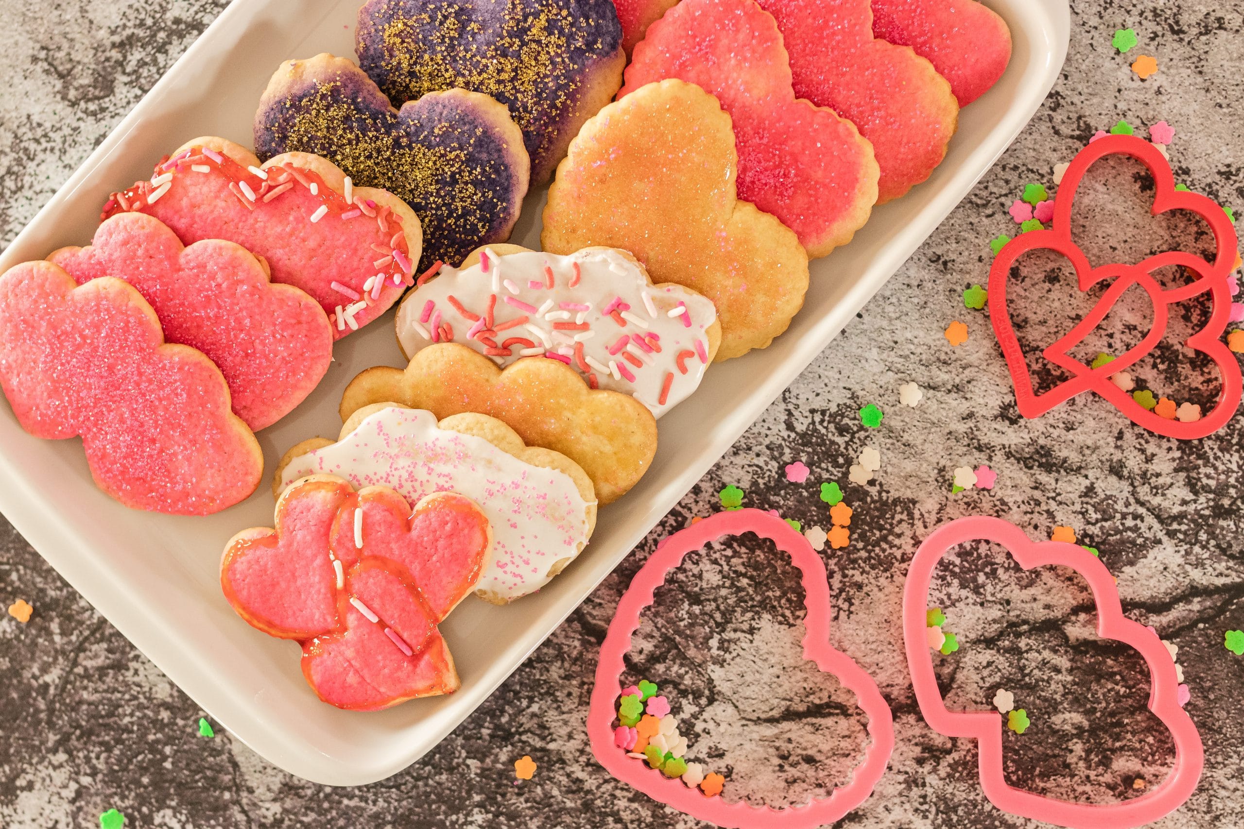 heart shaped Valentines Day Cookies on a tray with cookie cutters