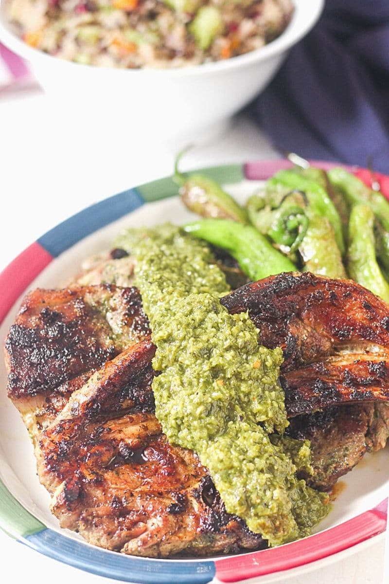 plate of grilled lamb chops with chimichurri and shishito peppers