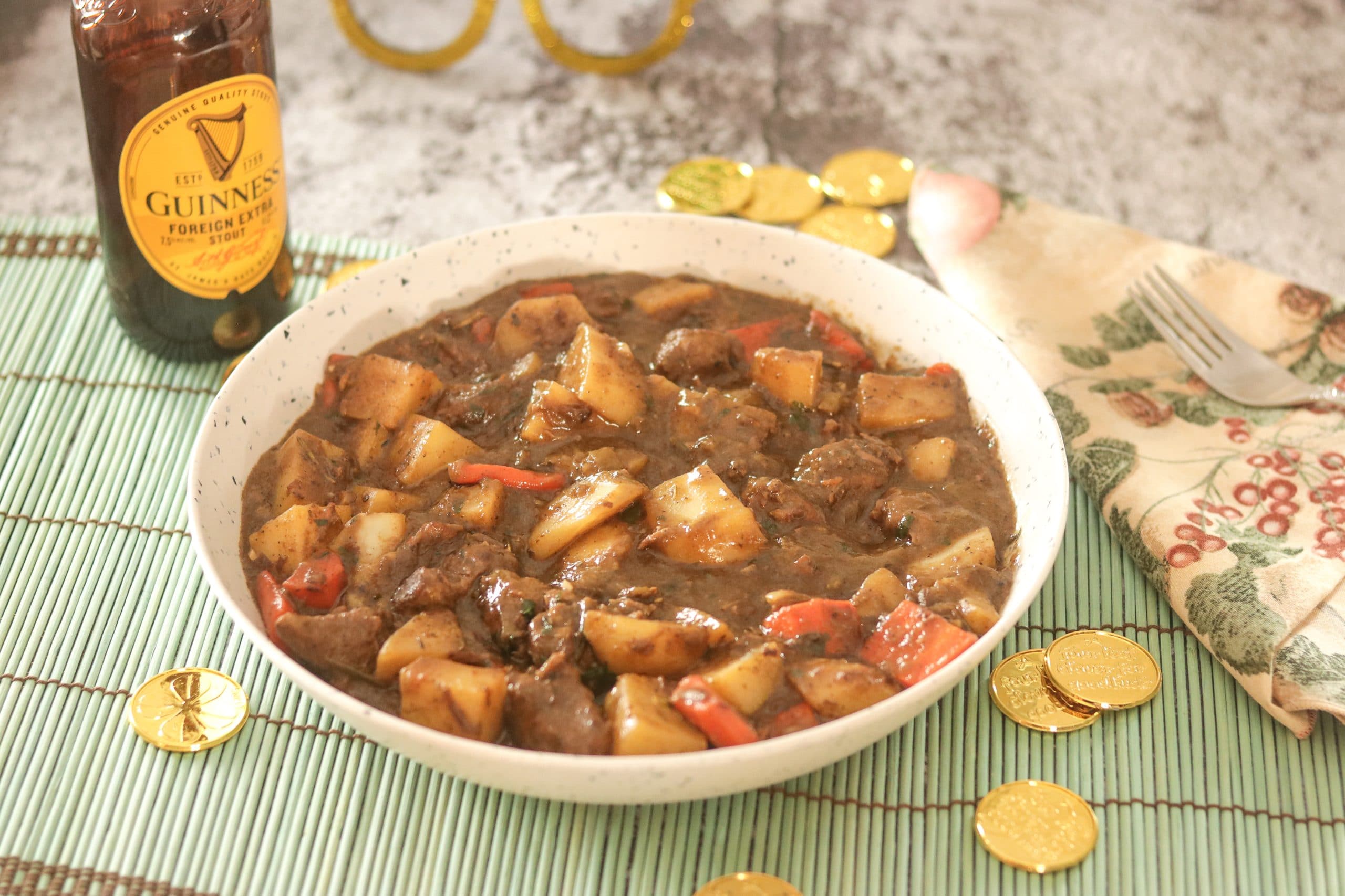 Irish Lamb Stew in a bowl with Guiness and gold coins in the background