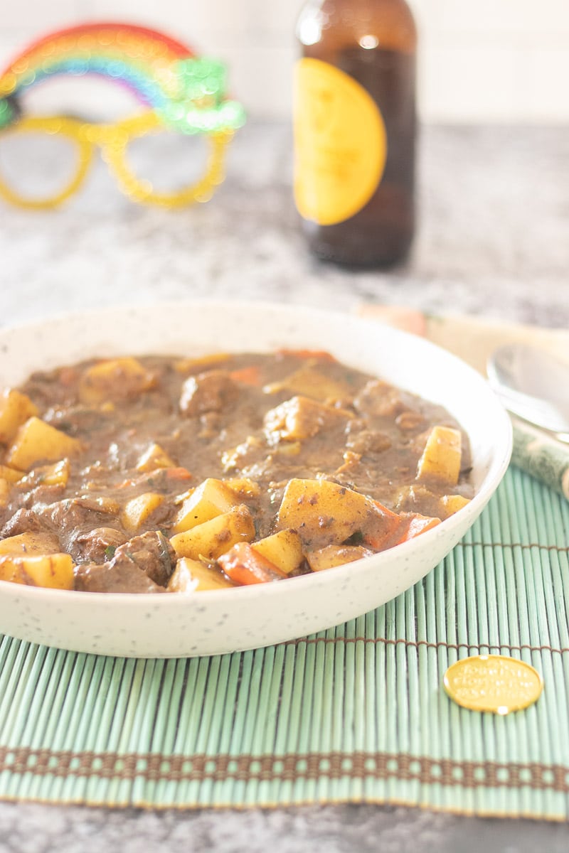 Irish Lamb Stew in a bowl with bottle of Guinness in background