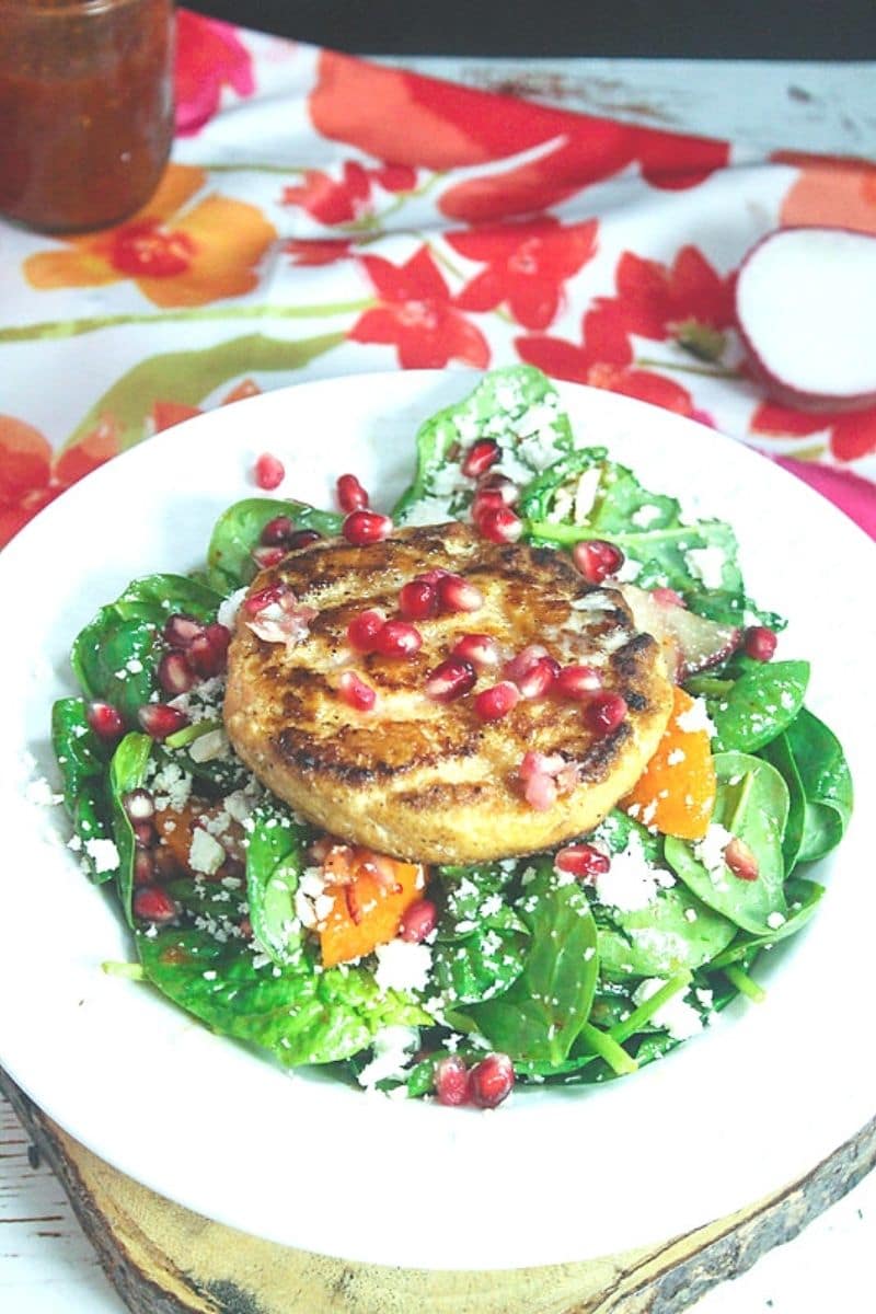 plate of Apricot Spinach Salad with salmon burger on top