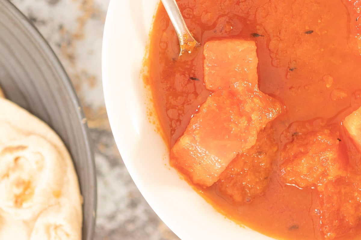 Watermelon Curry in a bowl with paratha in t he background