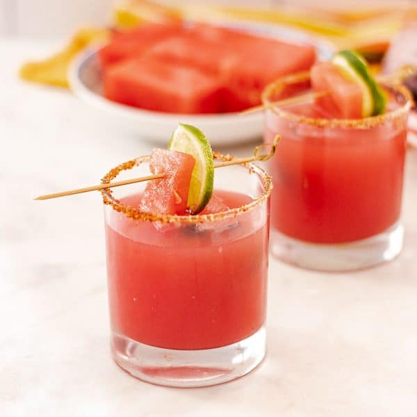 glasses of watermelon margarita with lime garnish and Tajin rim