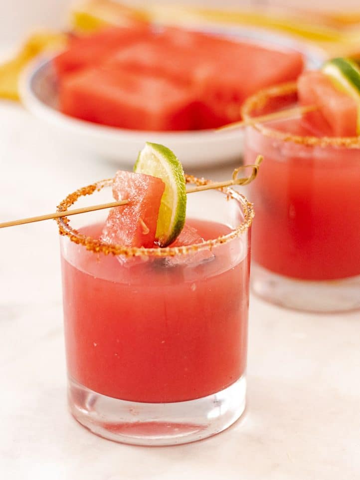 glasses of watermelon margarita with lime garnish and Tajin rim