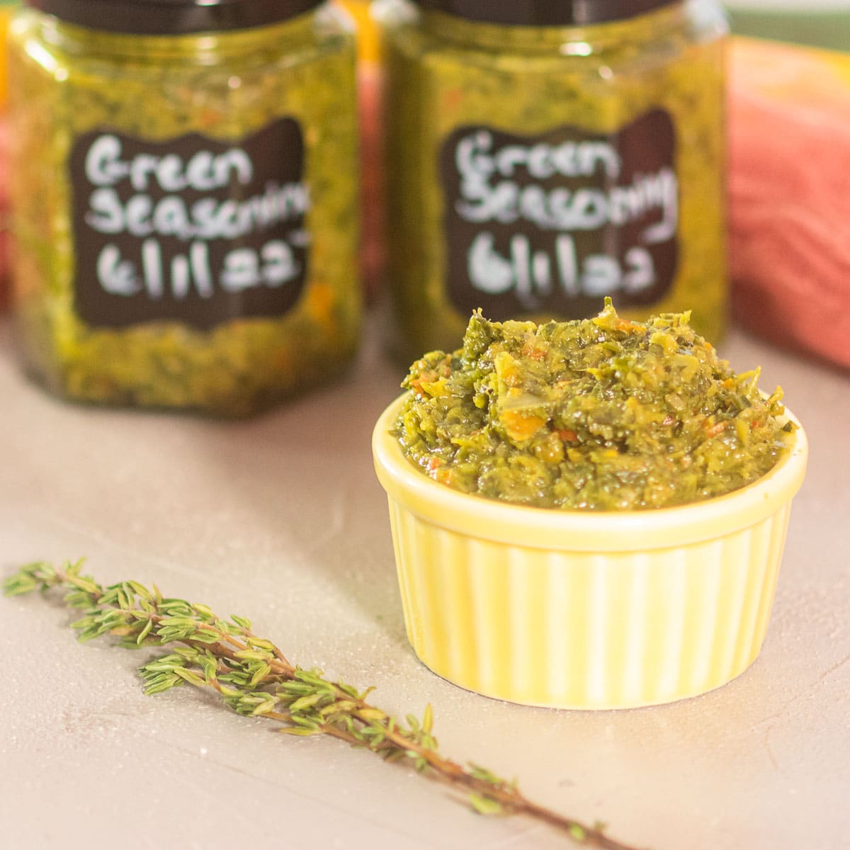 Green Seasoning in a small bowl with labeled jars in the back