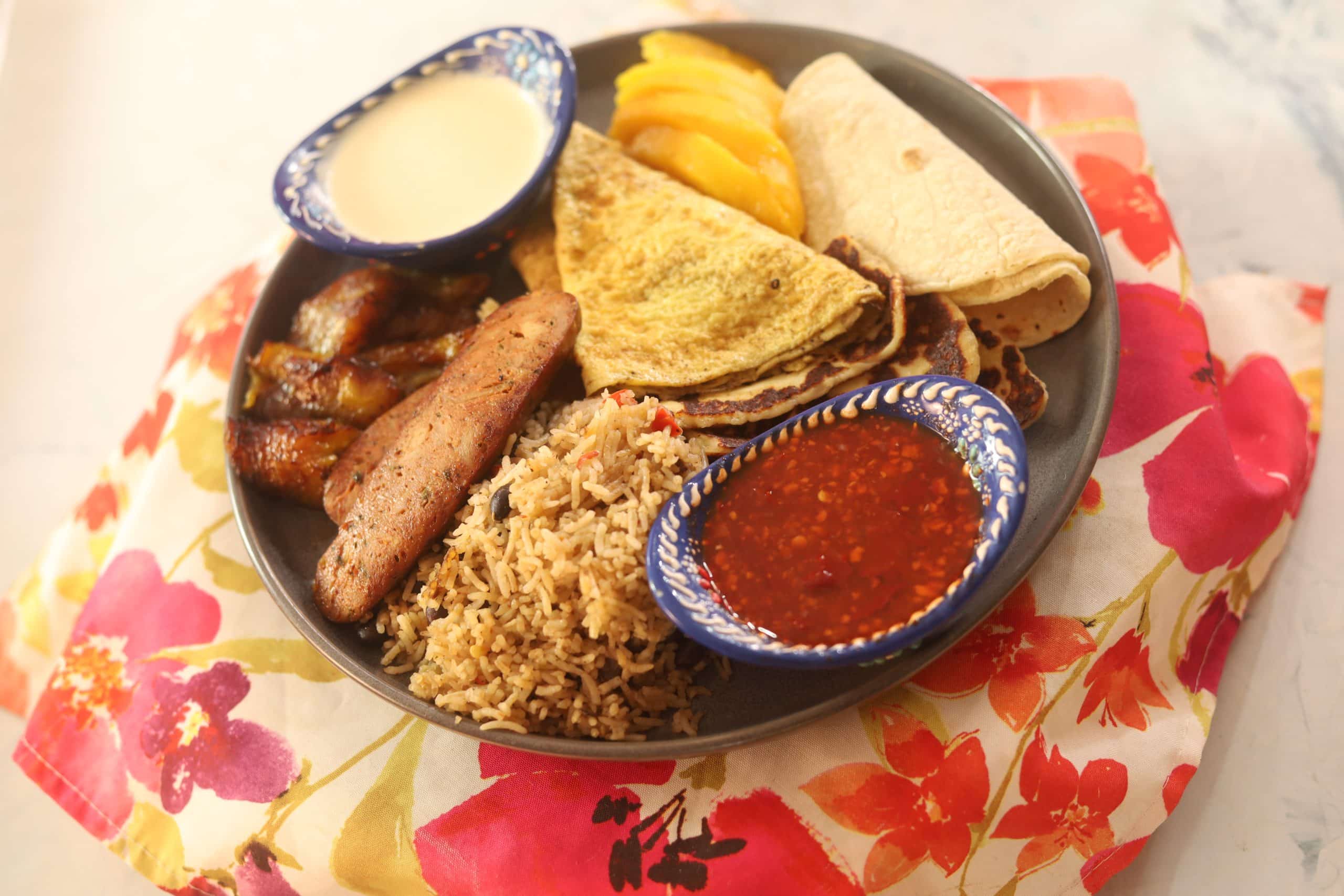 Costa Rican Breakfast Platter with Salsa Lizano, Galo Pinto, Chorizo, Tortillas, Fruit, Fried Plantain and Crema