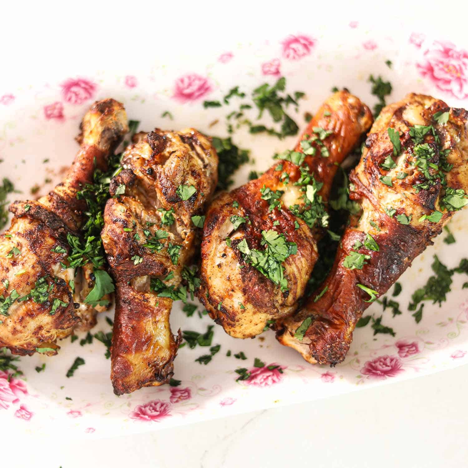 Masala Chicken Legs Recipe cooked in the Air Fryer on a plate garnished with chopped cilantro leaves.